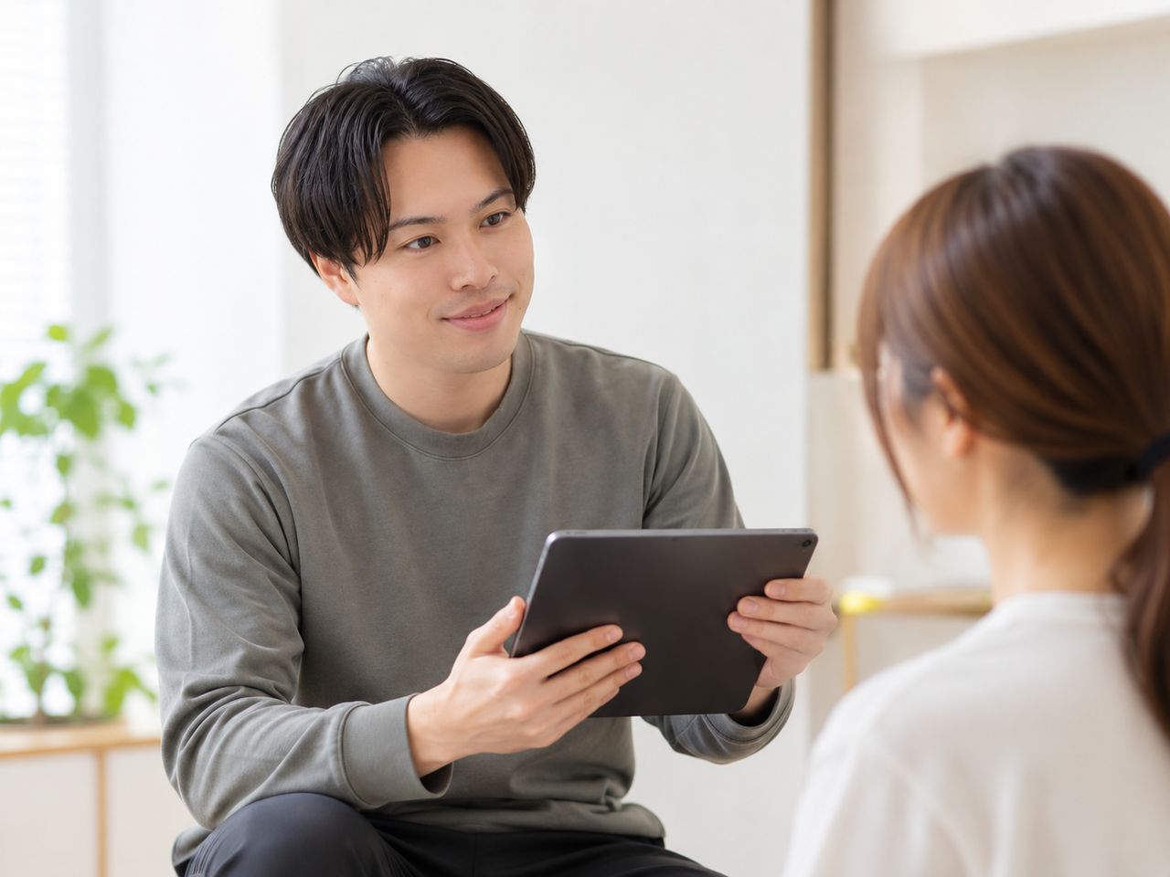 タブレットを見せながら説明する場面のイメージ