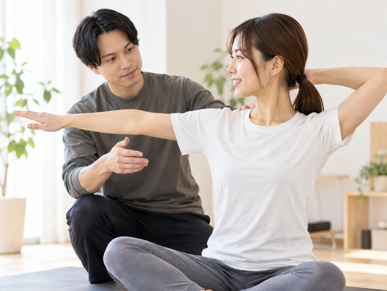 座った姿勢で腕を伸ばす動きを指導する場面のイメージ